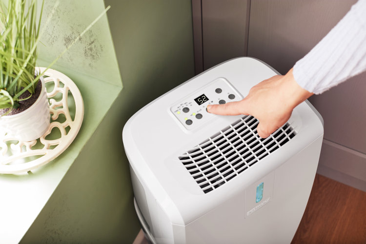 woman programming a dehumidifier in a laundry room