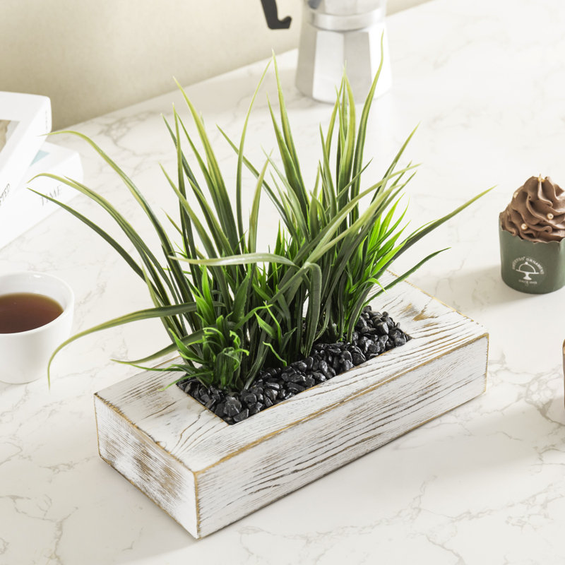 Herbes vertes artificielles dans un pot à fleurs en bois