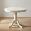 Ensemble de salle à manger 3 pièces en bois massif blanc lin, avec table ronde et 2 chaises à pied central en similicuir.