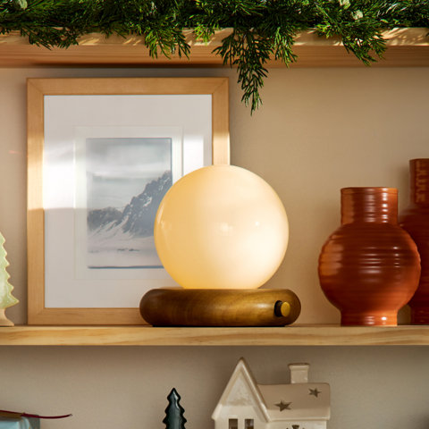Four modern table lamps with various styles including a metal dome lamp, a fabric-shaded cylinder lamp, and two small mushroom-style accent lamps displayed on tiered white pedestals.