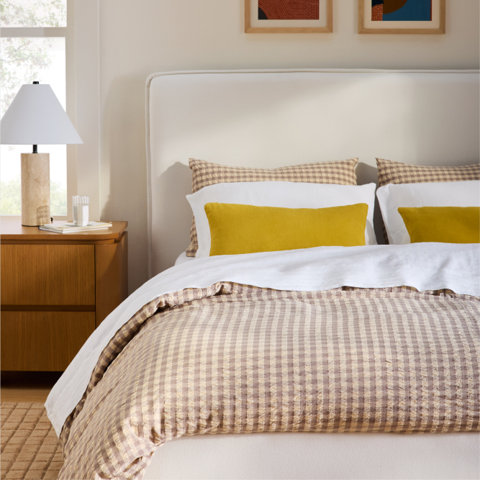 Bed with gingham duvet cover, mustard lumbar pillows.
