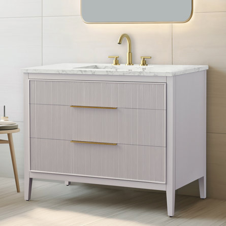 Bathroom vanity with white marble countertop and gold faucet.