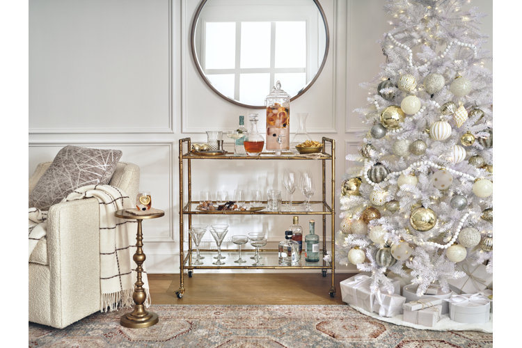 White christmas tree decorating ideas with a white christmas tree with gold silver and rose gold ornaments next to gold glam style bar cart and wall mirror
