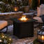 Table carrée pour foyer d'extérieur au propane avec base en osier, pierres de lave et patio extérieur