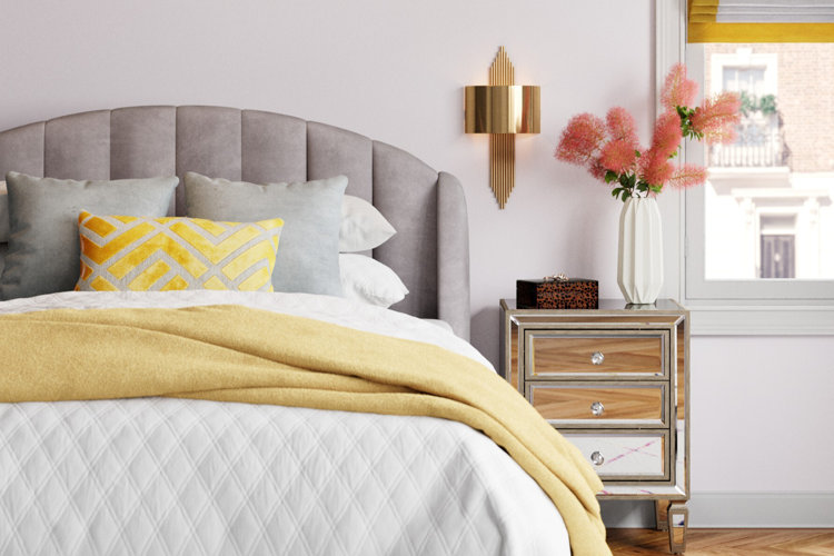 white quilt and yellow blanket on a gray upholstered bed