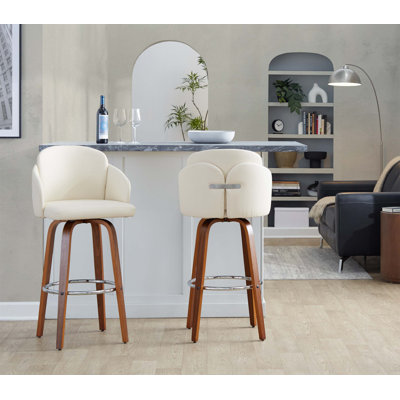 Ensemble de 2 tabourets pivotants à hauteur fixe avec structure en bois de noyer, siège en similicuir crème et repose-pieds rond chromé pour un bar ou un îlot de cuisine.