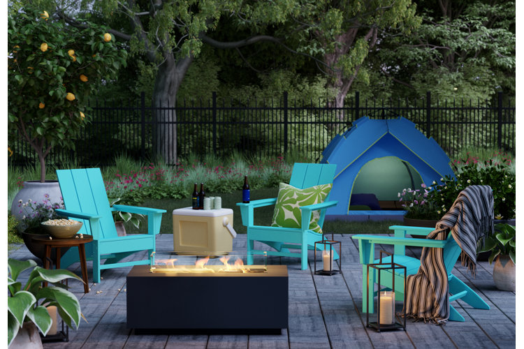 Backyard patio with three blue adirondack chairs around a modern firepit and a blue tent in the background.