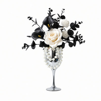 Composition florale artificielle noire et blanche, composée de roses blanches artificielles, de callas noirs et d'eucalyptus, avec vase en forme de gobelet argenté et décorations de perles. Décoration de table idéale pour un mariage, une fête ou toute autre occasion.