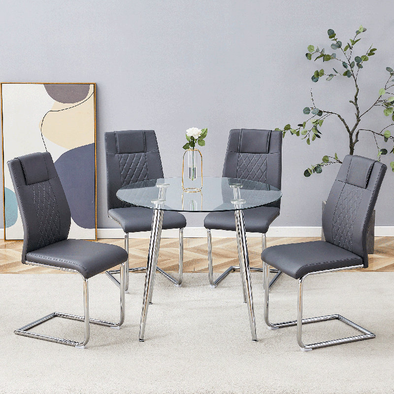 Ensemble de table et de chaises. Une table ronde minimaliste moderne en verre trempé transparent avec des pieds en métal argenté et 4 chaises de salle à manger à dossier haut en cuir synthétique gris pour une expérience luxueuse.