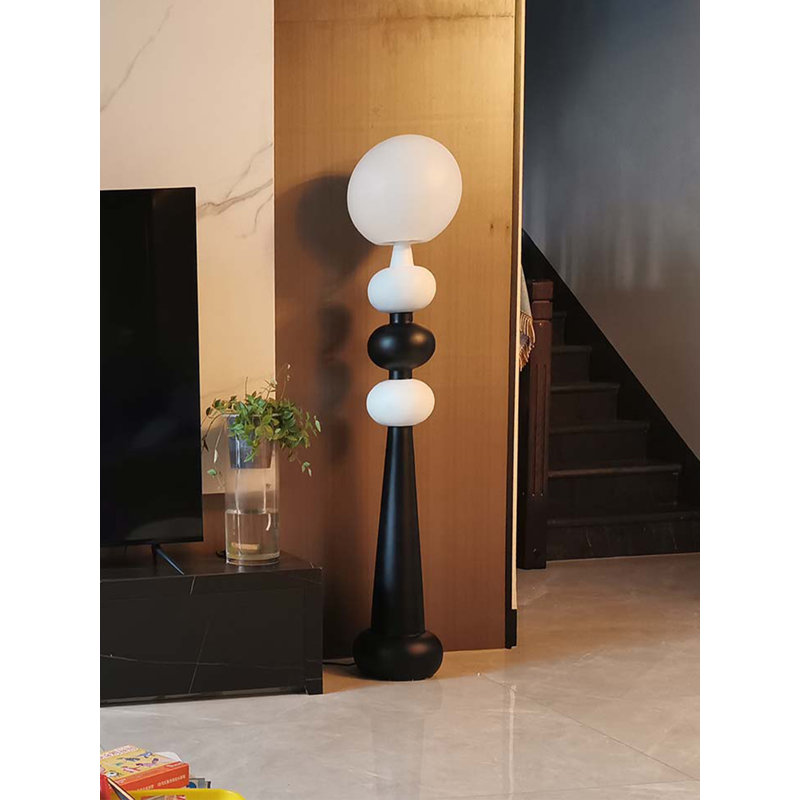 Lampe sur pied simple et moderne avec des éléments en verre et en fer forgé.
