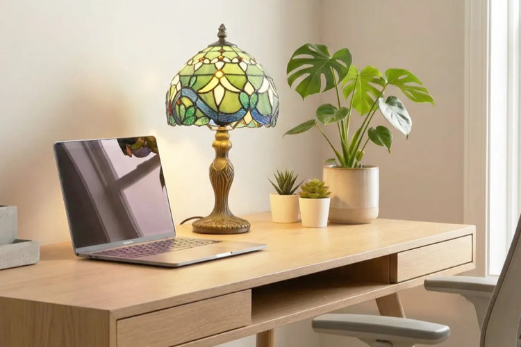 small blue and green Tiffany lamp with botanical and geometric patterns on a desk