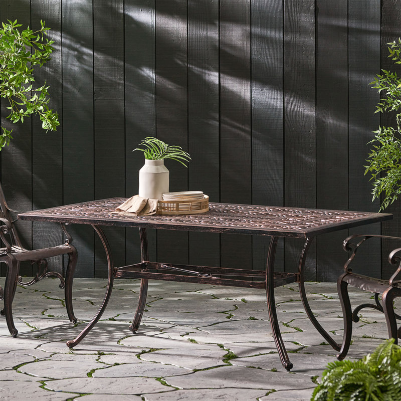Élégante table de salle à manger d'extérieur rectangulaire en fonte d'aluminium avec un design à coupe florale et une structure résistante à la rouille, parfaite pour recevoir jusqu'à 6 invités.