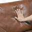 Sofa rustique deux places en similicuir au chocolat, avec accoudoirs droits et passepoil décoratif.