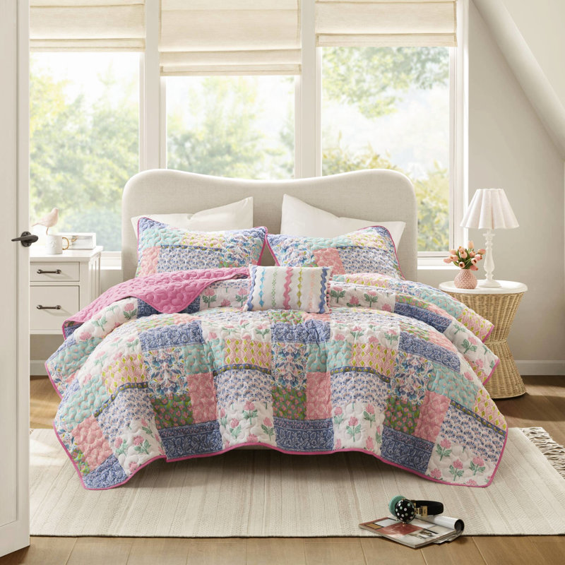 Couette rose à motifs floraux et à rayures audacieux, réversible pour une décoration polyvalente, en microfibre douce. Face avant patchwork ludique, revers uni apaisant. Confortable et facile à superposer.