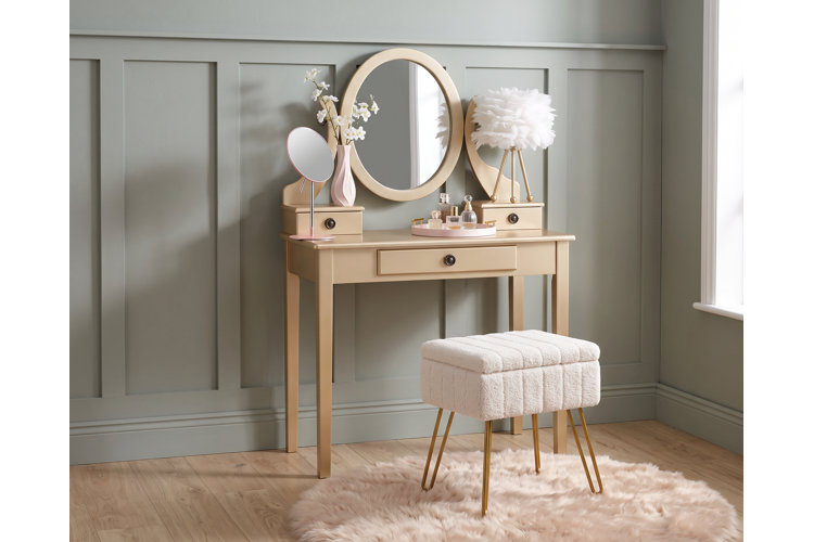 light wood makeup vanity with an ivory upholstered stool and pink makeup organizers in a traditional-style bedroom.