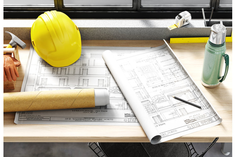 hard hat, tool box, and building floor plans on a wood workbench
