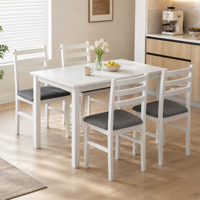 This white, compact five-piece farmhouse-style dining set includes a rectangular table and four upholstered chairs, perfect for small apartment or kit
