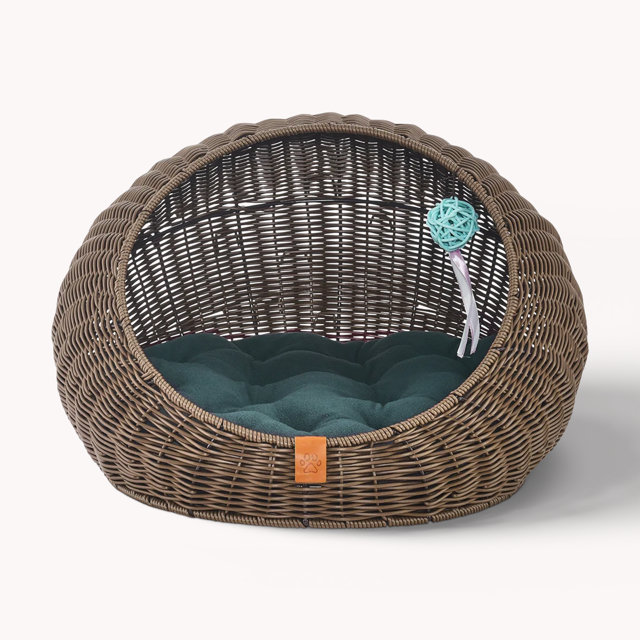 Wicker pet cave bed with green cushion and toy