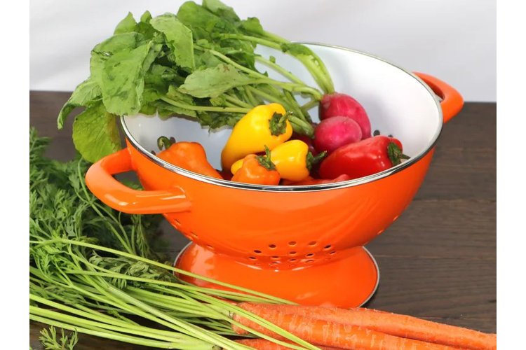 orange colander with freshly washed vegetables inside