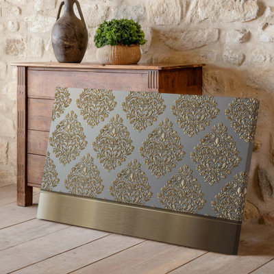 La toile crée un design de papier peint élégant avec un motif damassé complexe en or chatoyant contre un taupe doux