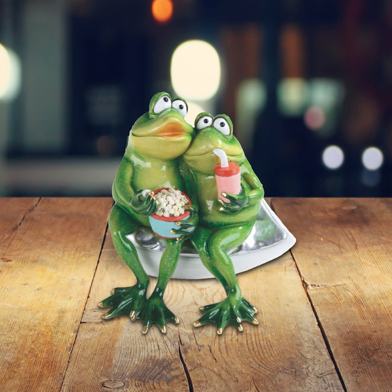 Figurine de grenouille romantique regardant un film avec maïs soufflé et figurine de soda