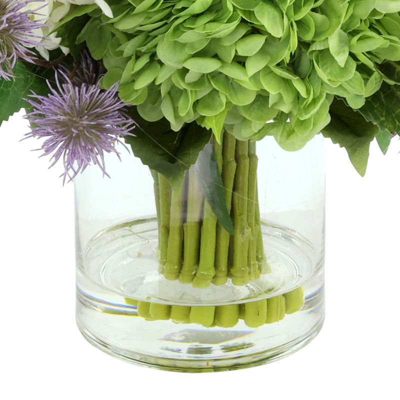 Hortensia, chardon et rose disposés dans un vase en verre