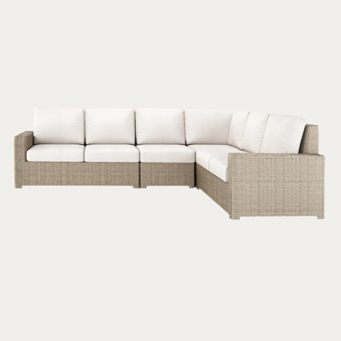 Wicker outdoor sectional sofa with white cushions.