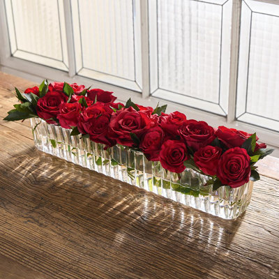 Arrangement de roses dans un vase en verre nervuré rouge