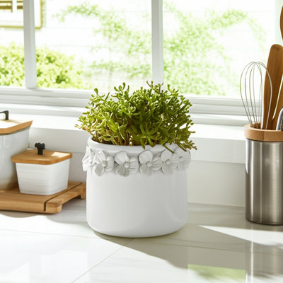 Pot de fleurs rond en céramique avec bordure florale sculptée et trou de drainage pour présentation décorative ou support pour plante