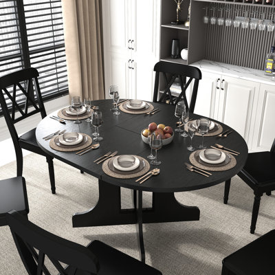 Table de salle à manger élégante, ovale extensible de 150 x 109 cm, rallonge amovible, piètement en X noir, 6 places assises, aspect attrayant.
