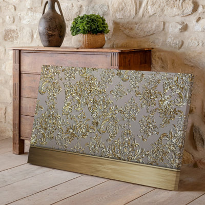 La toile crée un design de papier peint élégant avec un motif damassé complexe en or chatoyant contre un taupe doux