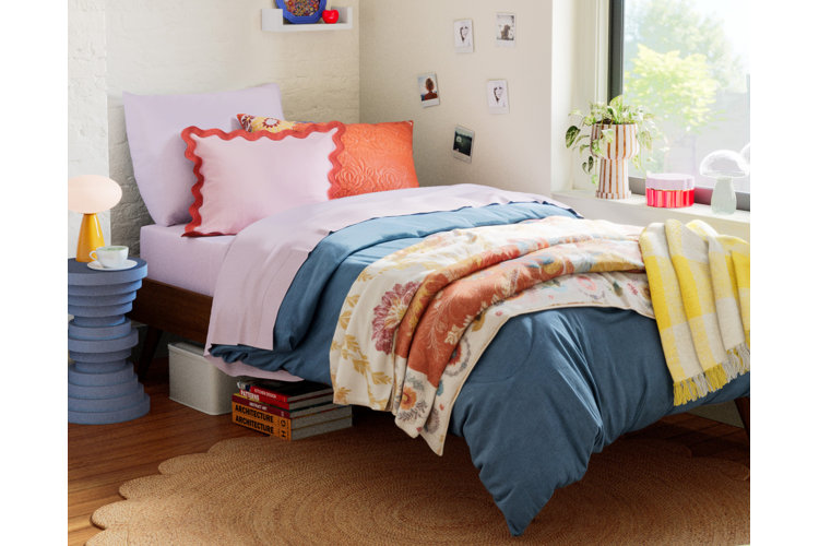 girls dorm room with blue comforter, photo wall art, and under bed storage
