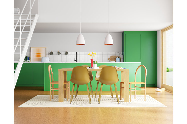 Modern open floor plan kitchen and dining area with green cabinets, wood table, yellow chairs, pendant lighting, and neutral rug defining space