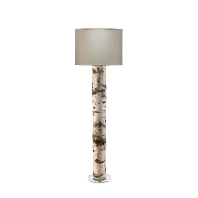 Floor lamp with a cylindrical base featuring a natural white birch wood bark texture and a simple beige drum shade on a circular clear base.