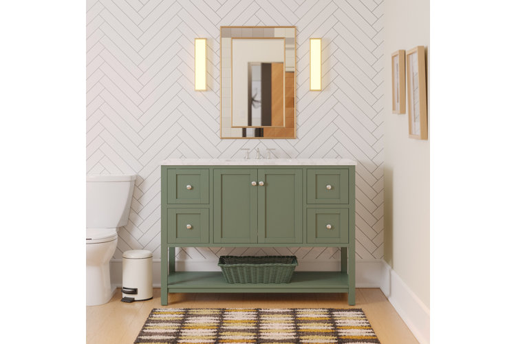 modern bathroom with white tiles, green vanity, and gold metal framed mirror