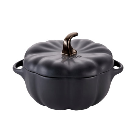 Staub matte black ceramic pumpkin-shaped cocotte with a metallic stem handle isolated on a white background.