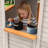 KizzParnrr Elevated Wooden Kids Playhouse with Wave Slide, Wrap-Around Deck, Flat-Step Ladder, Half Door Windows, Vertical Speed Slide Pole and Sandbox, for Outdoor Backyard Play