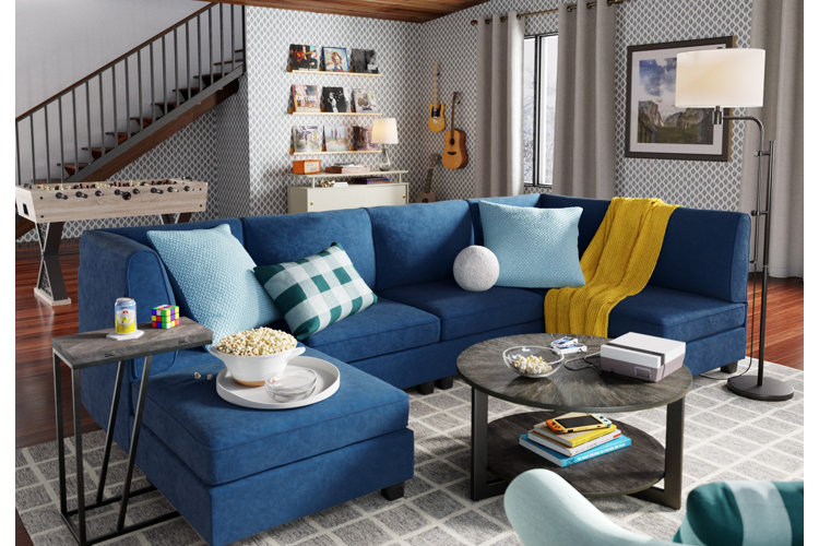 Man cave with a blue sectional, a foosball table, a wall-mounted record display, and two wall-mounted guitars.