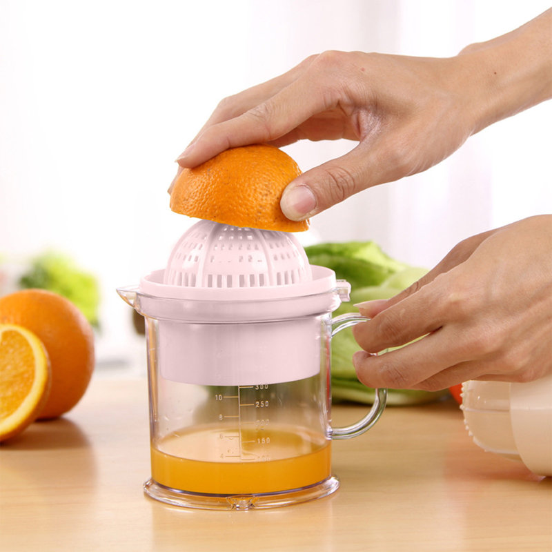 Presse-agrumes manuel pressant la tasse à citron avec balance tenant la main et pressant le jus, Pink