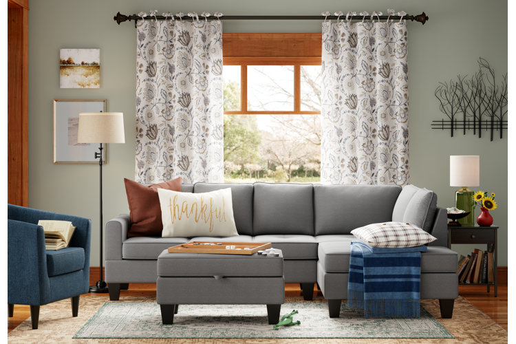 cozy living room with area rug layered over carpet and a gray sectional and matching ottoman