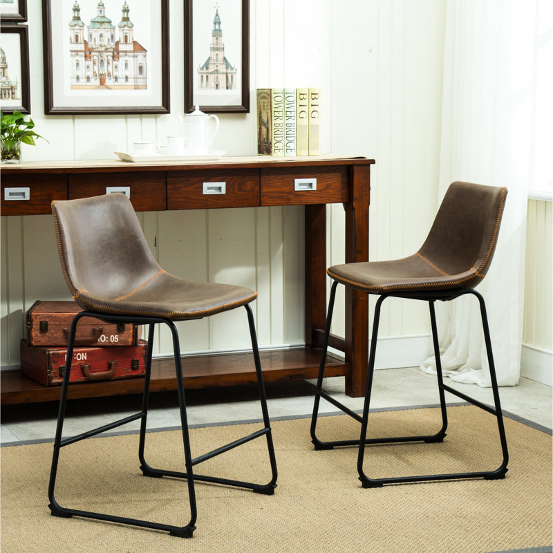 De 2 tabourets de comptoir en cuir brun antique. Fabriqué à la main avec base en plastique et en polyuréthane rétro. Cadre en fer noir. Dimensions: l 18,5 po x P 21,5 po x H 34,5 po. Siège: 2 tabourets de H 24,5 po x P 15 po. Revêtement en cuir