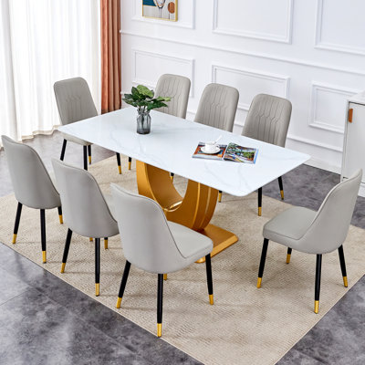 Ensemble de table et de chaises. Table de salle à manger moderne en verre à texture de pierre blanche avec pattes en U dorées et pattes en métal gris clair et pieds en métal noir.