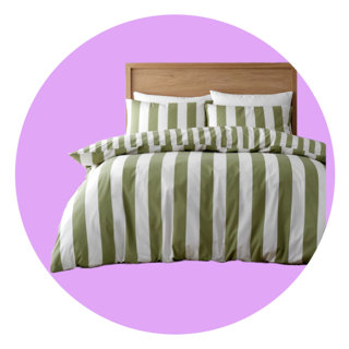 Bed dressed in an olive green and white striped duvet cover and matching pillowcases against a light wood headboard, set against a circular lilac background.