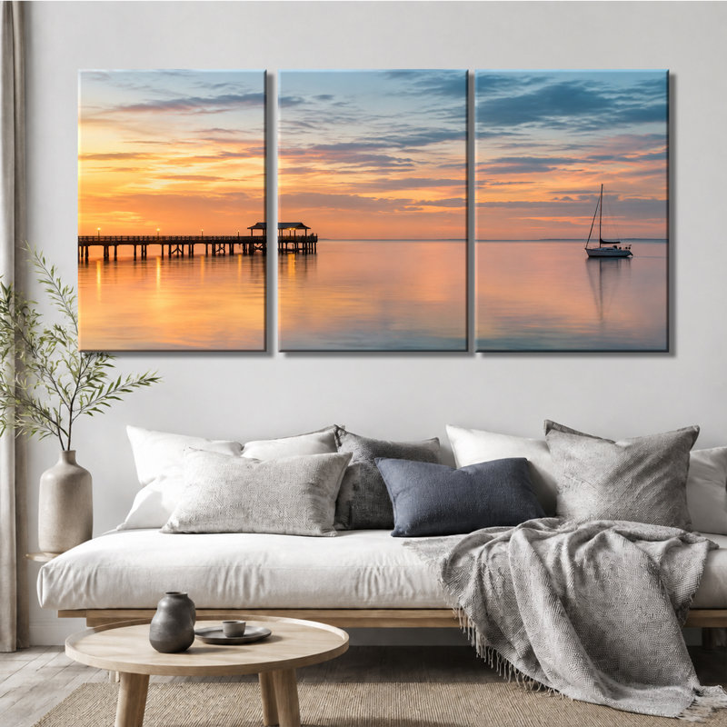 Tableau en trois panneaux représentant un voilier au coucher du soleil sur la jetée, imprimé sur une toile tendue