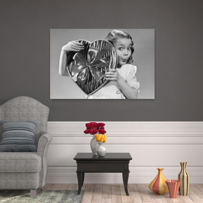 1950s Surpris petite fille regardant la caméra par derrière un grand cœur en forme de boîte de bonbons Saint-Valentin, rétro, rétro, art mural