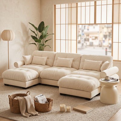 Canapé modulaire 3 places en velours crème, avec 2 poufs amovibles, coussins de dossier et traversins.