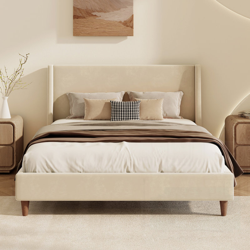 Lit plateforme tapissier en velours crème avec tête de lit à oreilles et pieds en bois de noyer