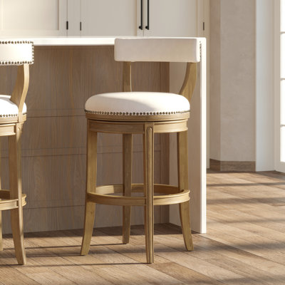 Tabouret de bar avec siège d'une hauteur de 31 pouces, finition pacane, retour automatique à 180 degrés de sa position idéale, siège rembourré en similicuir gris, structure en bois à dossier ouvert, garniture cloutée entourant les pieds incurvés 31