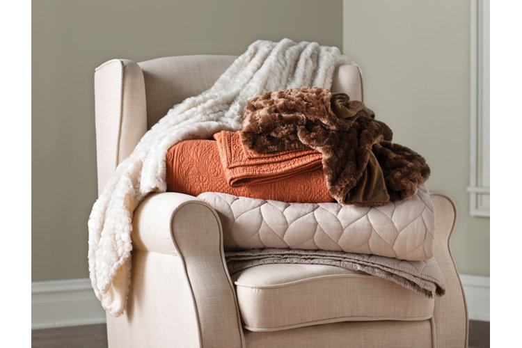 chair with a stack of folded throw blankets