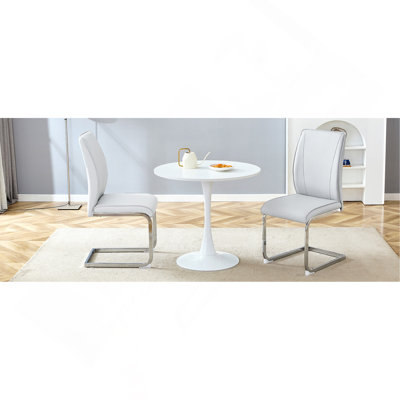 Ensemble de table et de chaises. Petite table ronde stable en forme de verre - 31,9 po x 31,9 po avec 2 chaises en polyuréthane gris clair douces et confortables avec des pieds arqués en métal argenté. Créez votre espace de luxe exclusif et discret.
